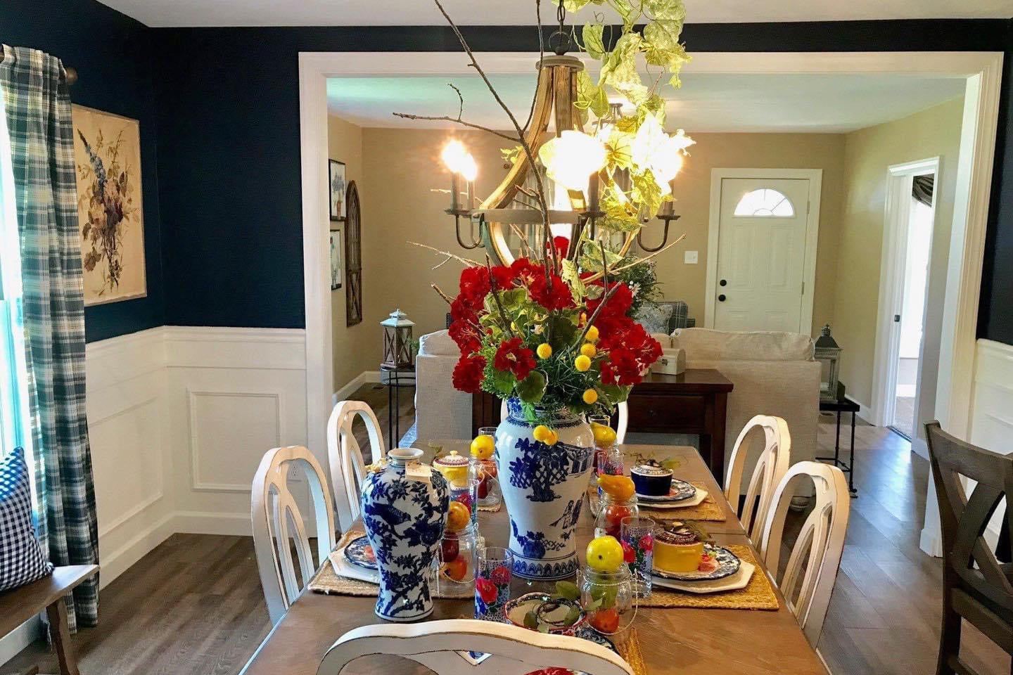 Dining room with a table set for a meal, featuring flowers and decorative items.