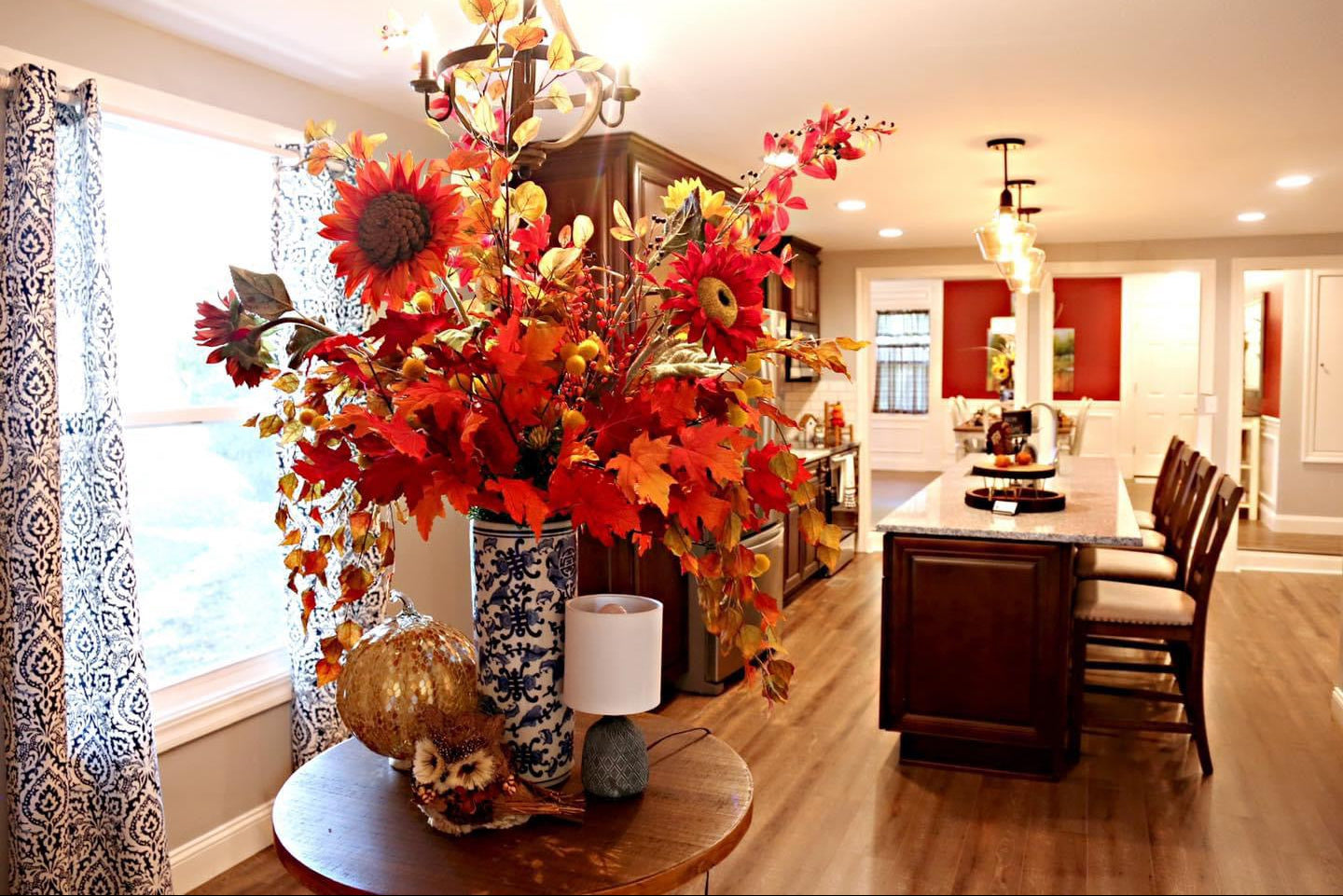 Decorative autumn-themed floral arrangement in a living room with a chandelier and table lamp.