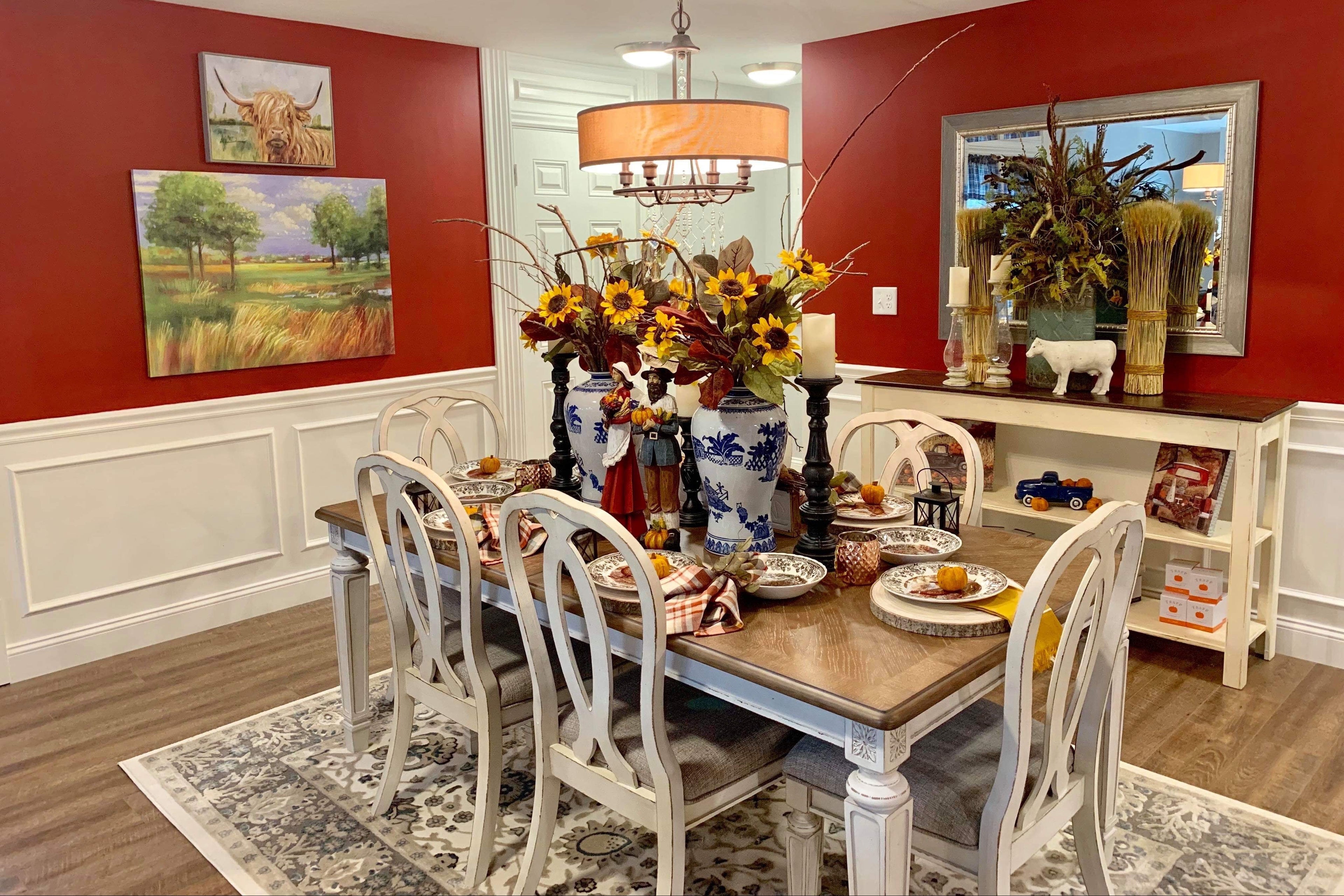 Dining room with red walls, white trim, and a wooden table set for a meal.