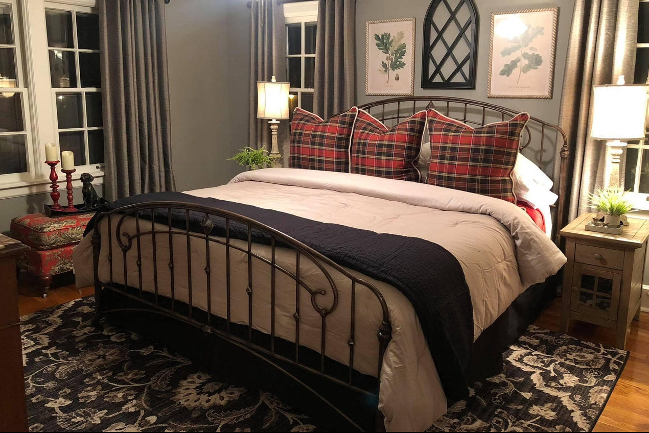 Bedroom with a bed featuring plaid pillows, nightstands, and decorative elements.