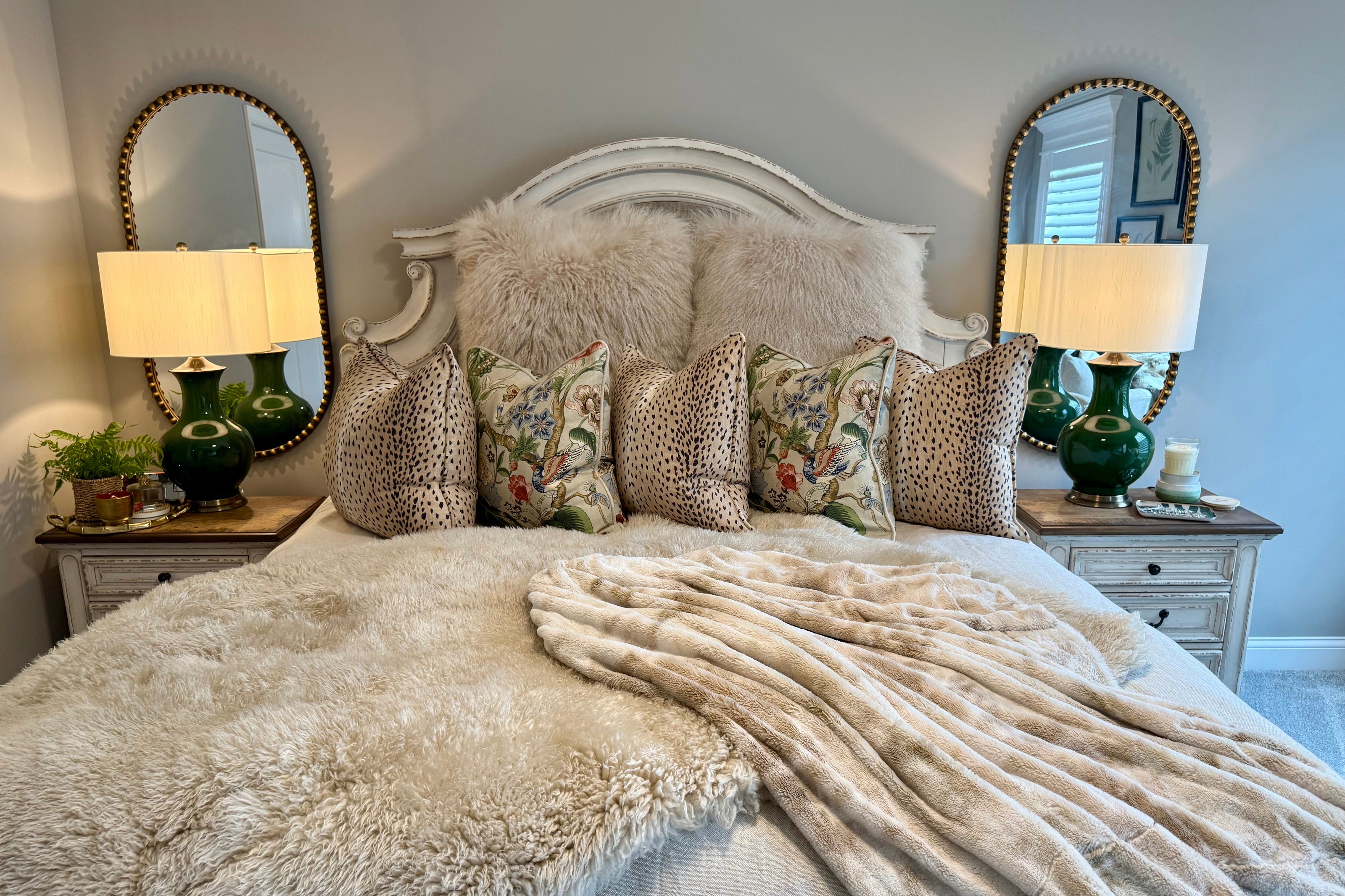 Neatly made bed with decorative pillows and a fluffy blanket in a bedroom setting.