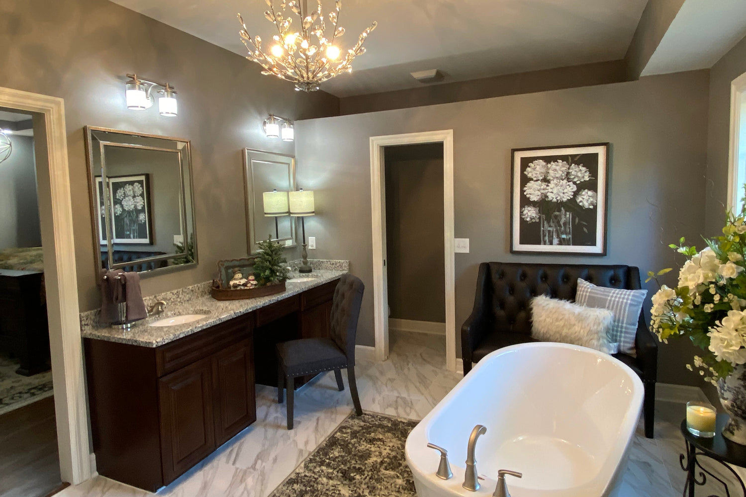 Luxurious bathroom with freestanding bathtub, vanity, and chandelier.