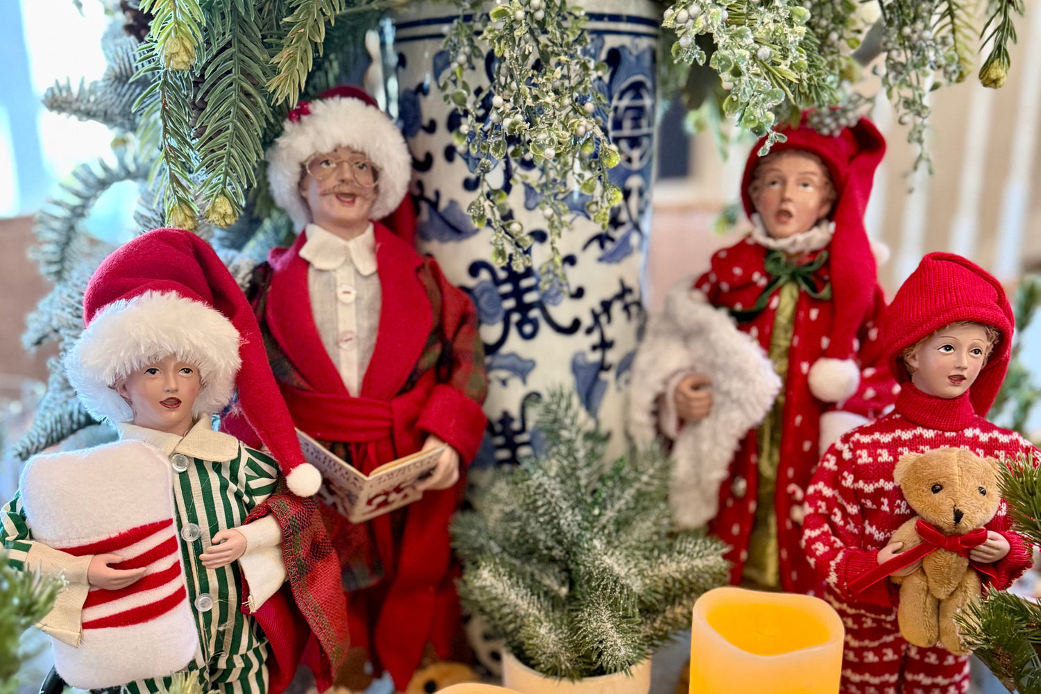Decorative Christmas scene with carolers, candles, and festive elements on a table.