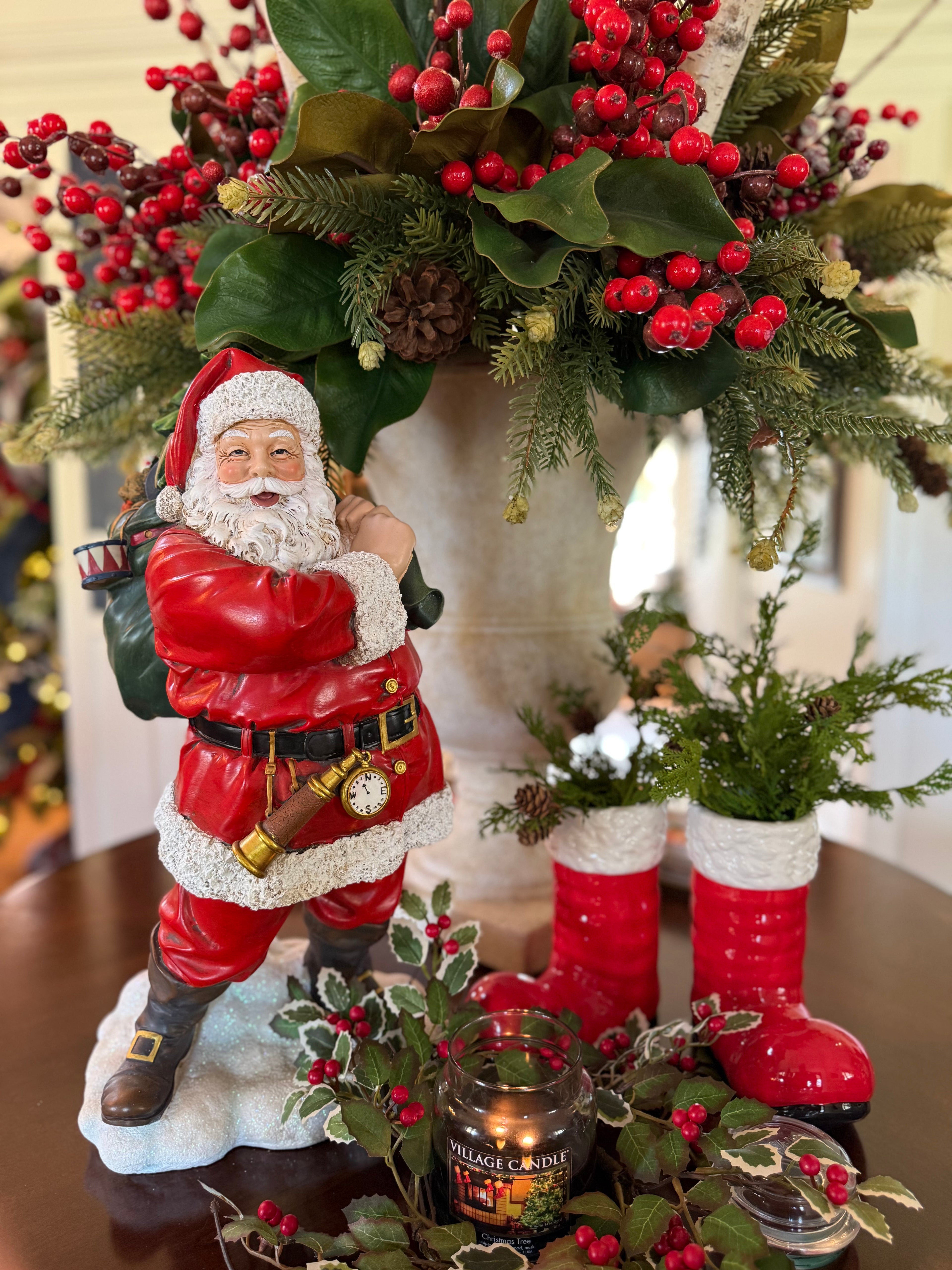 Decorative Santa Claus figure with red boots and greenery on a table.
