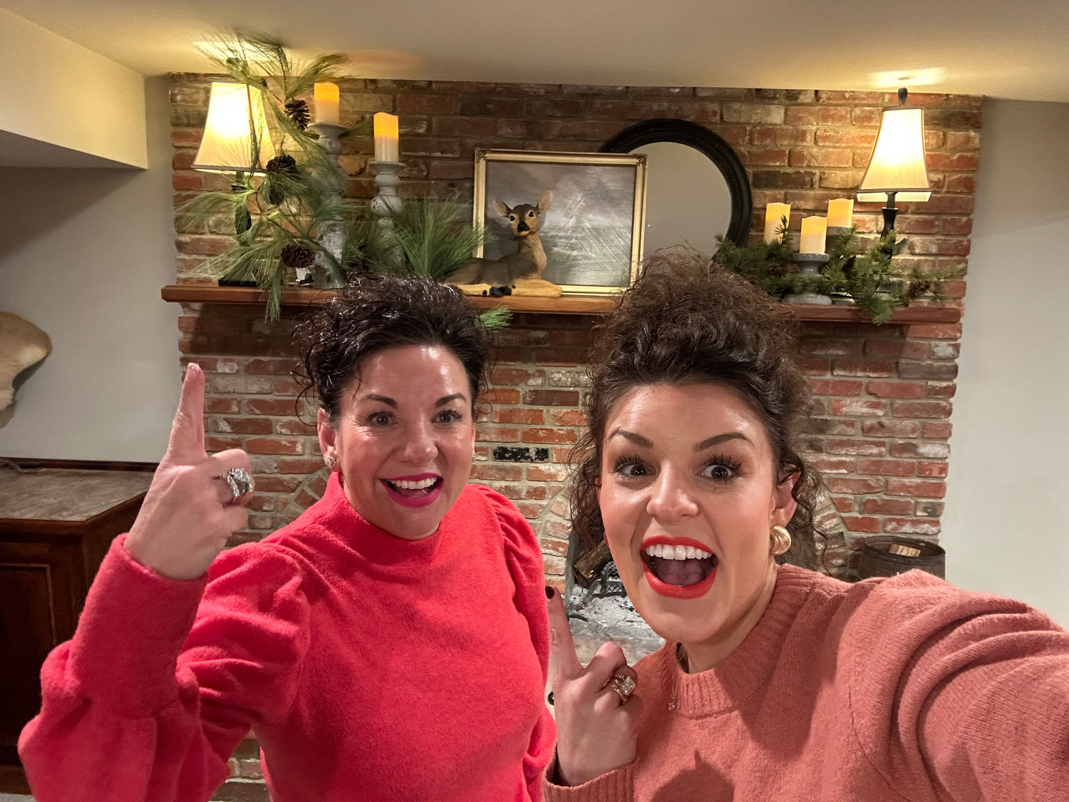 Two women in a room with a brick wall and decorative items.