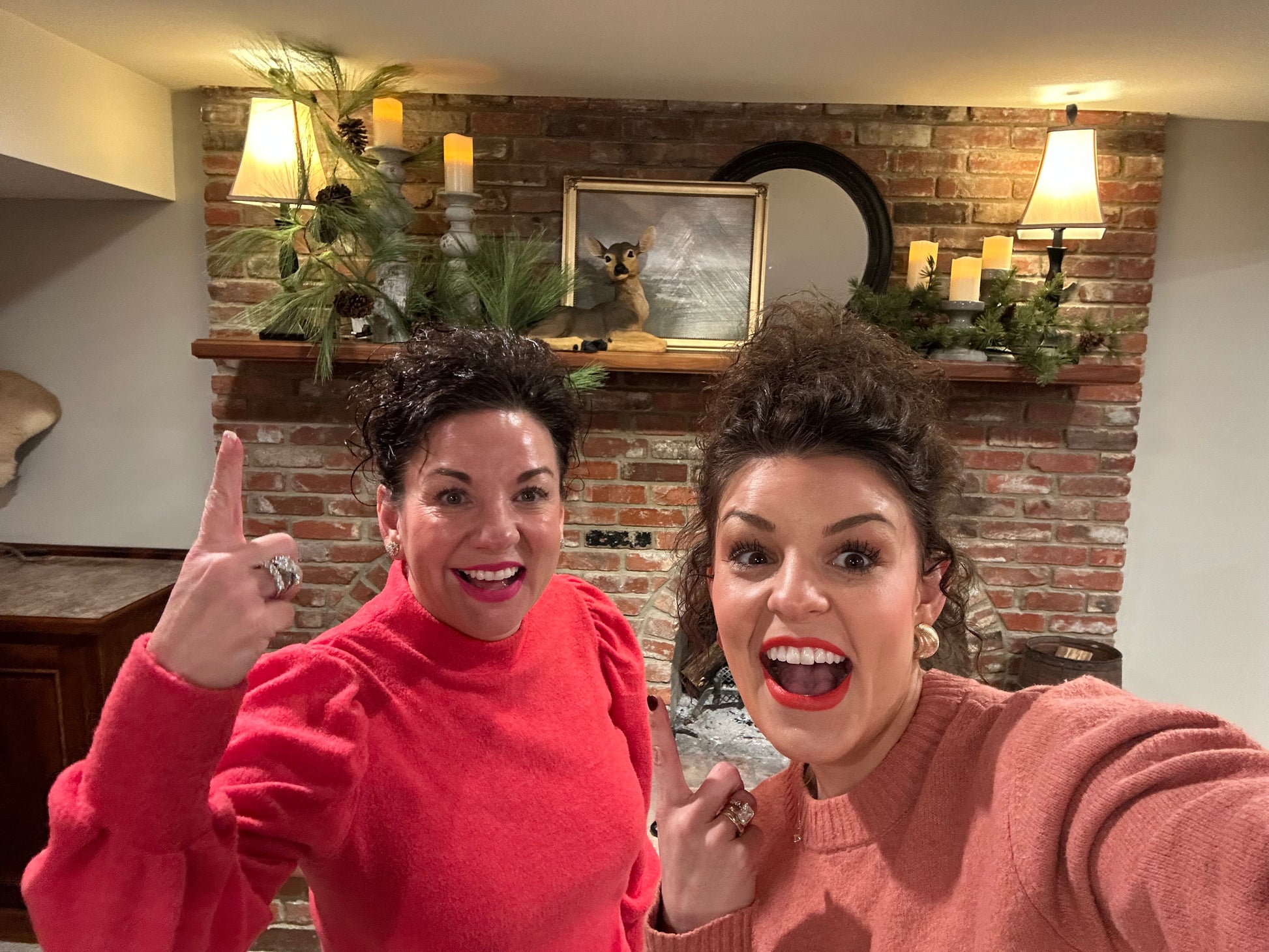 Two women in a room with a brick wall and decorative items.