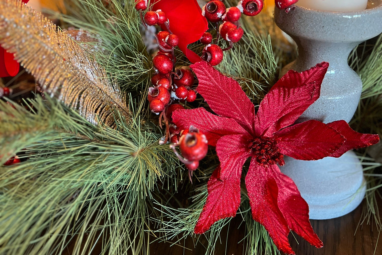 Red flower with red frosted berries in a floral arrangement. 