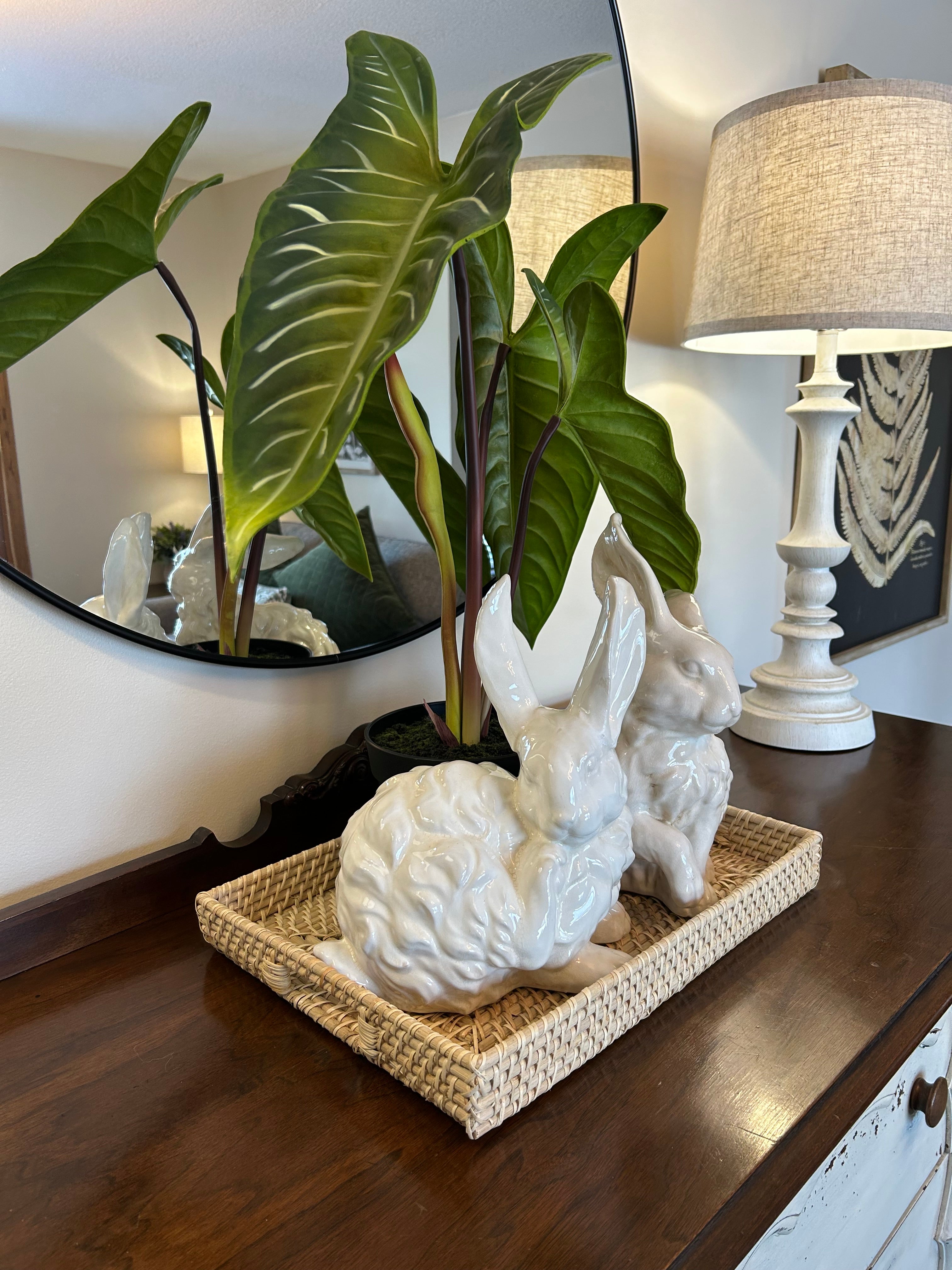 Decorative scene with a white sculpture, plant, and woven basket on a surface.