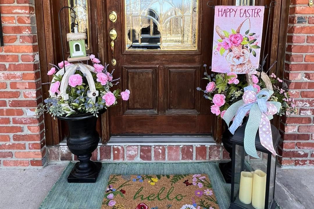 Decorative front door with Easter wreath, flowers, and candles on a brick house.