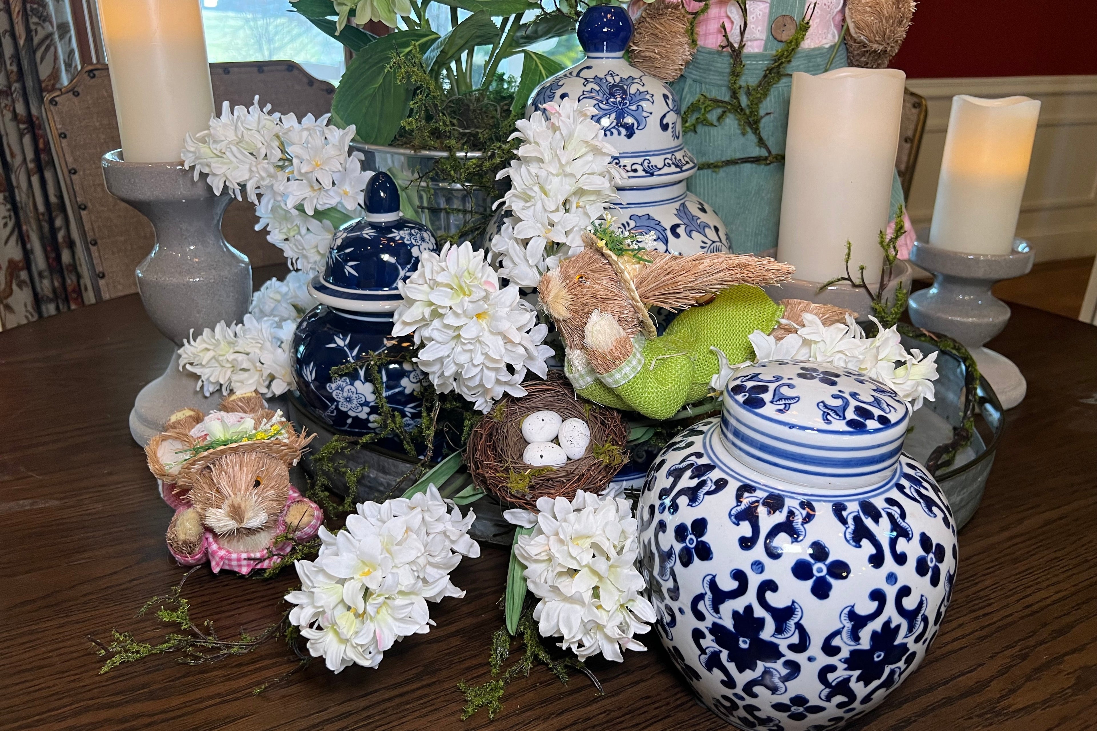 Decorative table setting with blue and white ceramic jars, teddy bears, and flowers.